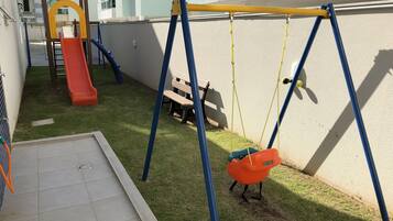 Children can play on the slide, swing set, and artificial grass area.