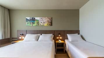A hotel room with two beds, a nightstand with a lamp, and a painting on the wall.
