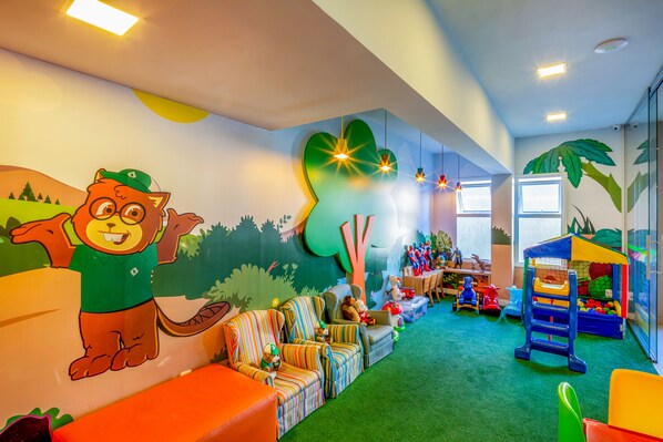 Un cuarto de juegos infantil con un mural, muebles coloridos y equipo de juegos.