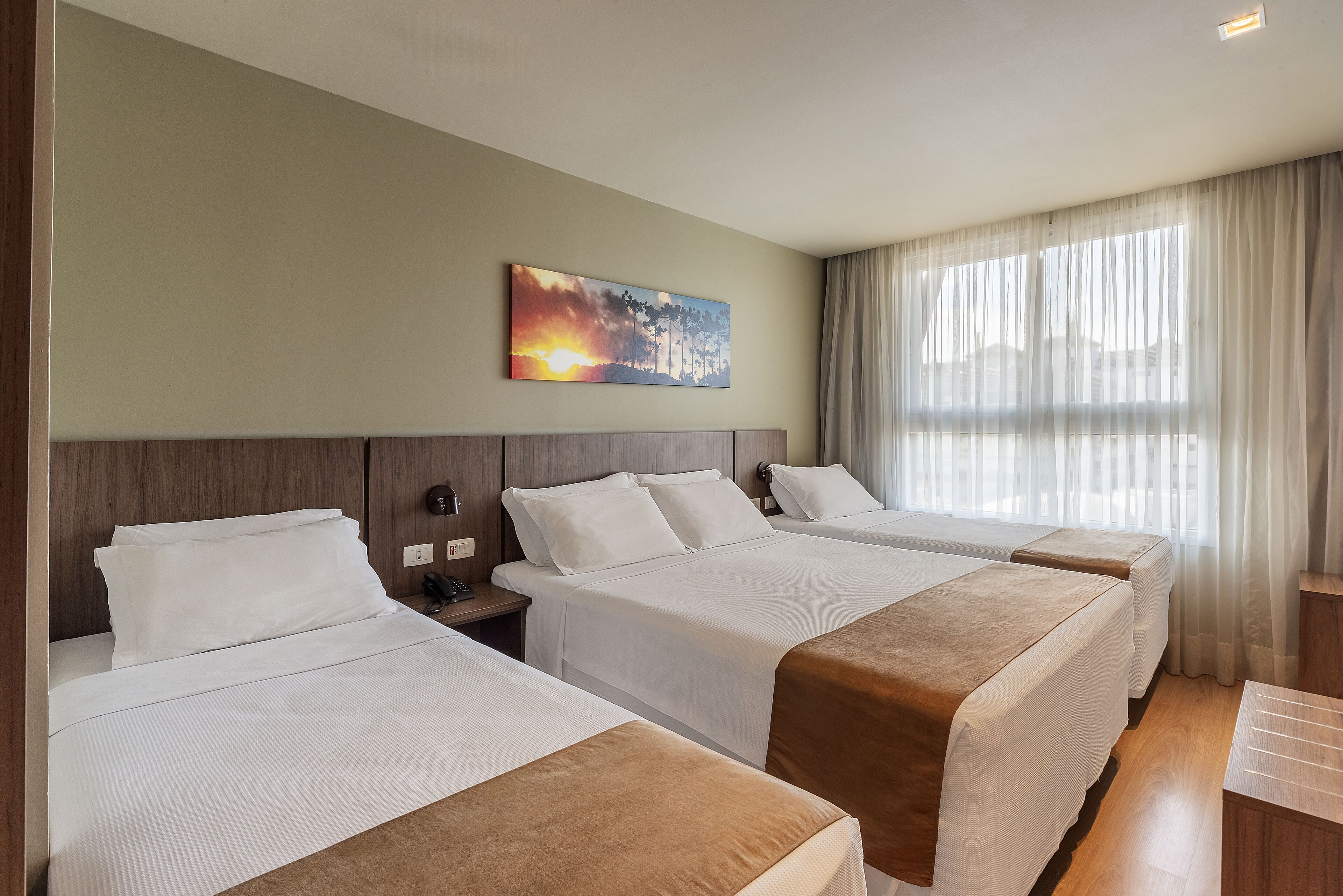 Ein Hotelzimmer mit zwei Betten, einem Bild an der Wand und einem großen Fenster mit Vorhängen.