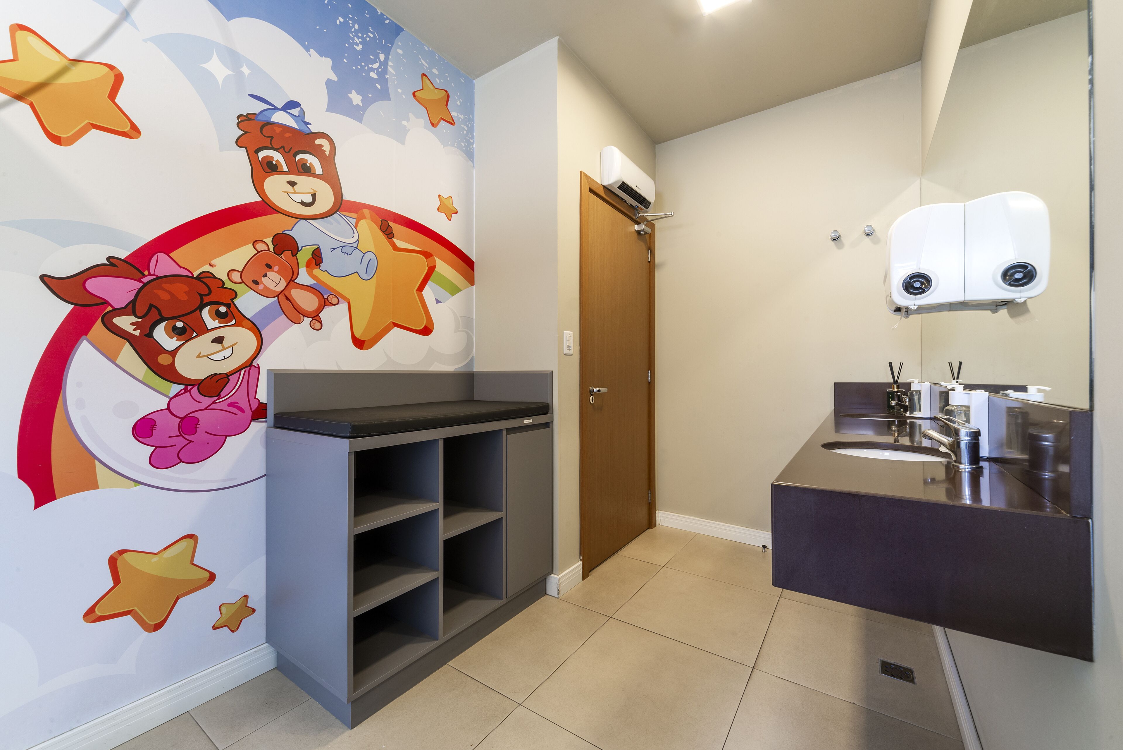 Une salle de bain avec un lavabo moderne, un miroir et un mur décoré de personnages de dessins animés.