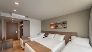 Een hotelkamer met twee bedden, een kledingkast, een bureau en een airconditioner.