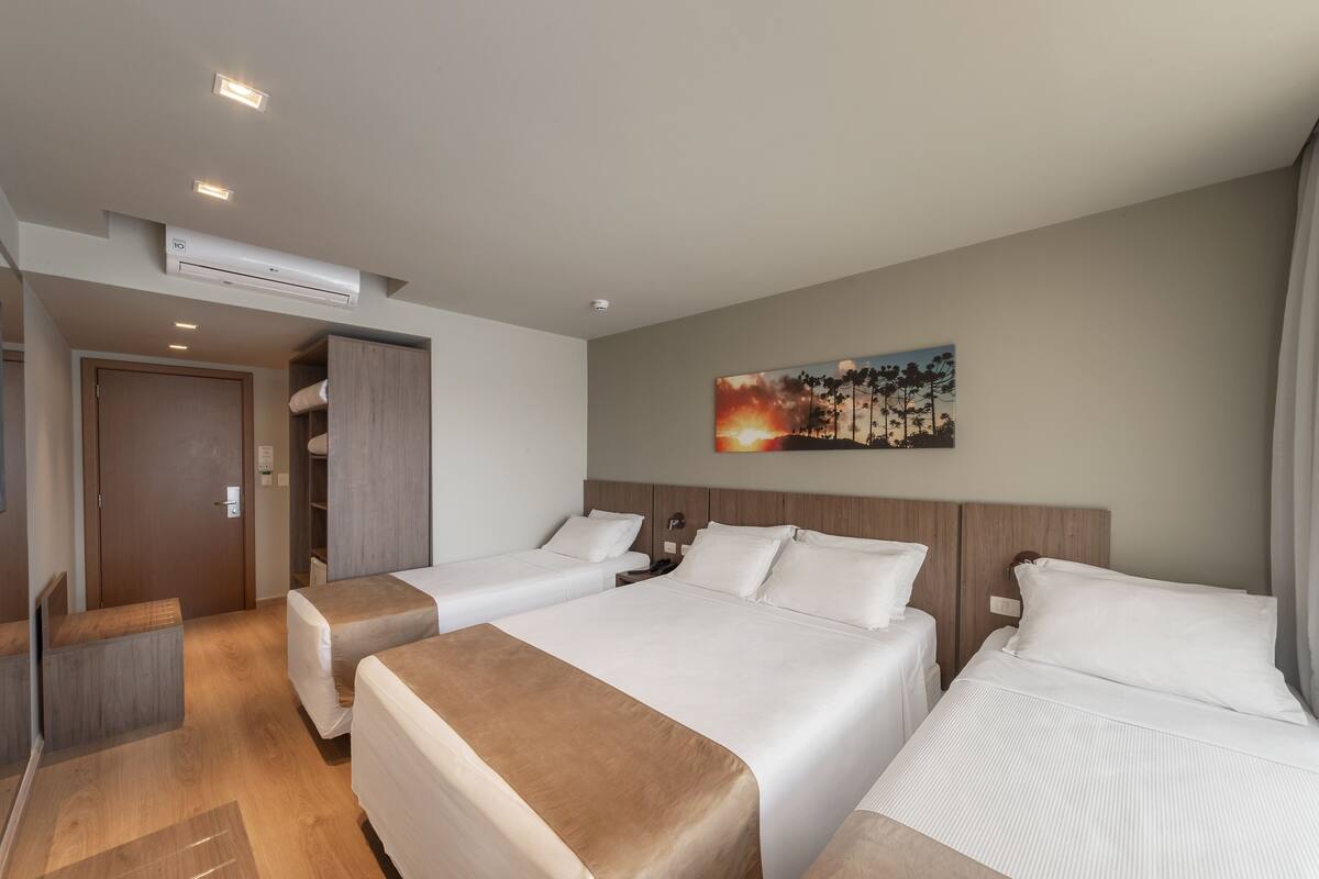Een hotelkamer met twee bedden, een kledingkast, een bureau en een airconditioner.
