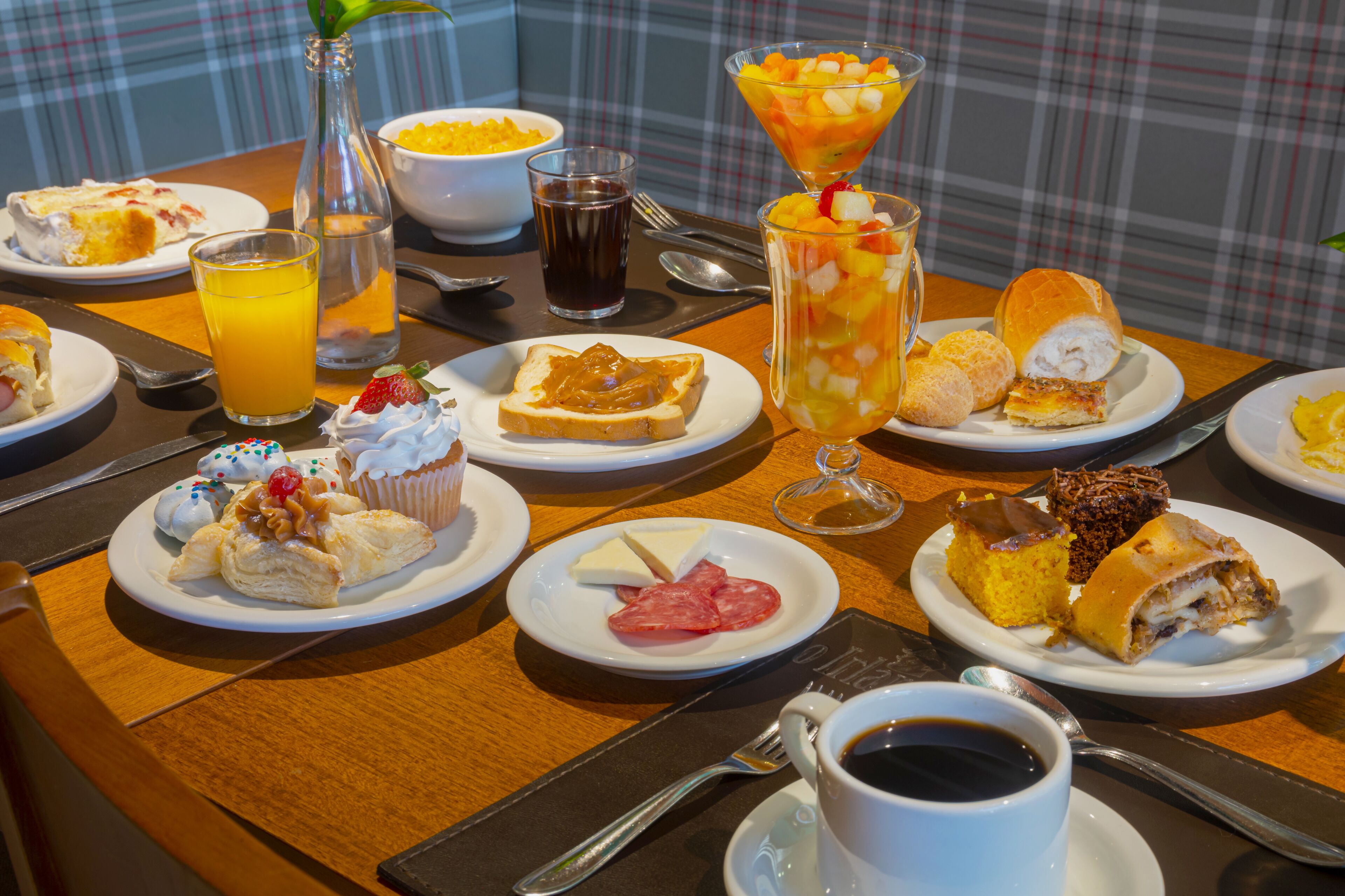 Un bufé de desayuno con diversos pasteles, frutas y bebidas.