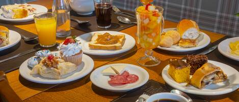 Un bufé de desayuno con diversos pasteles, frutas y bebidas.