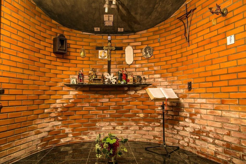 Eine Kapelle mit einer Ziegelwand, einem Kruzifix und einer Statue von Jesus.