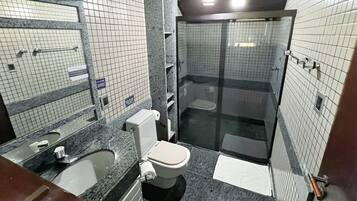 Un baño con inodoro, lavabo y zona de ducha.