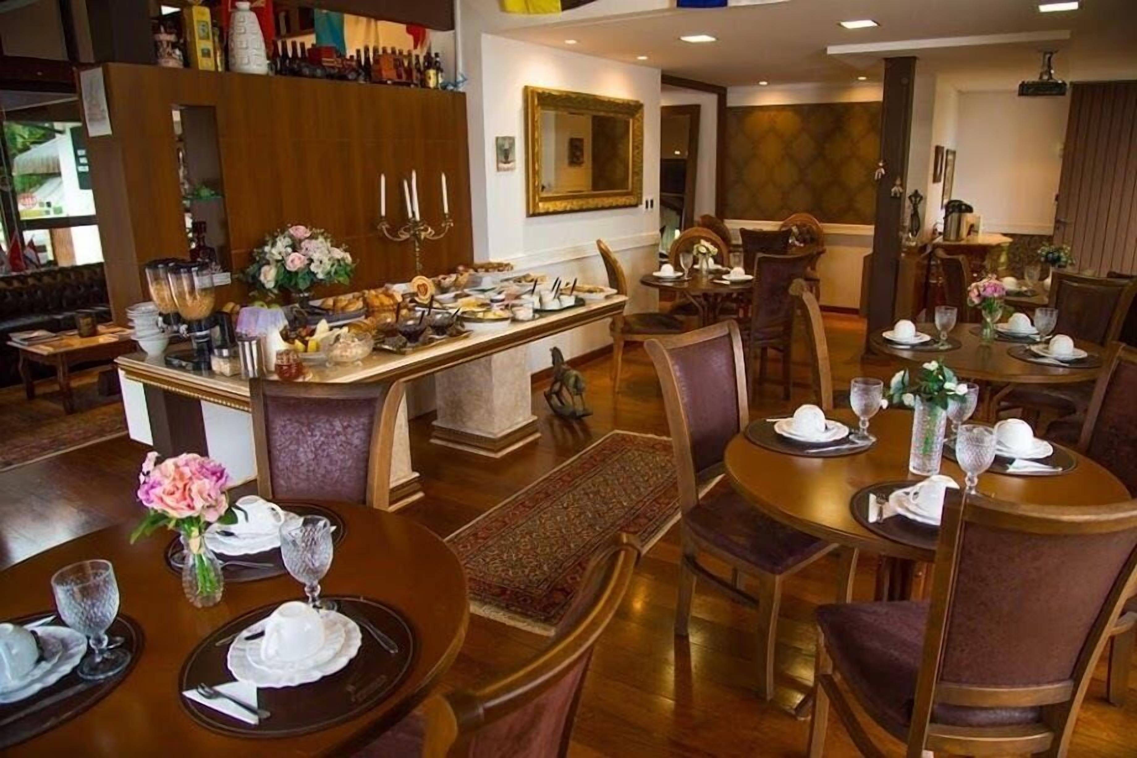 A dining area with round tables set for service, a bar area with a variety of food and drink items, and a mirror on the wall.