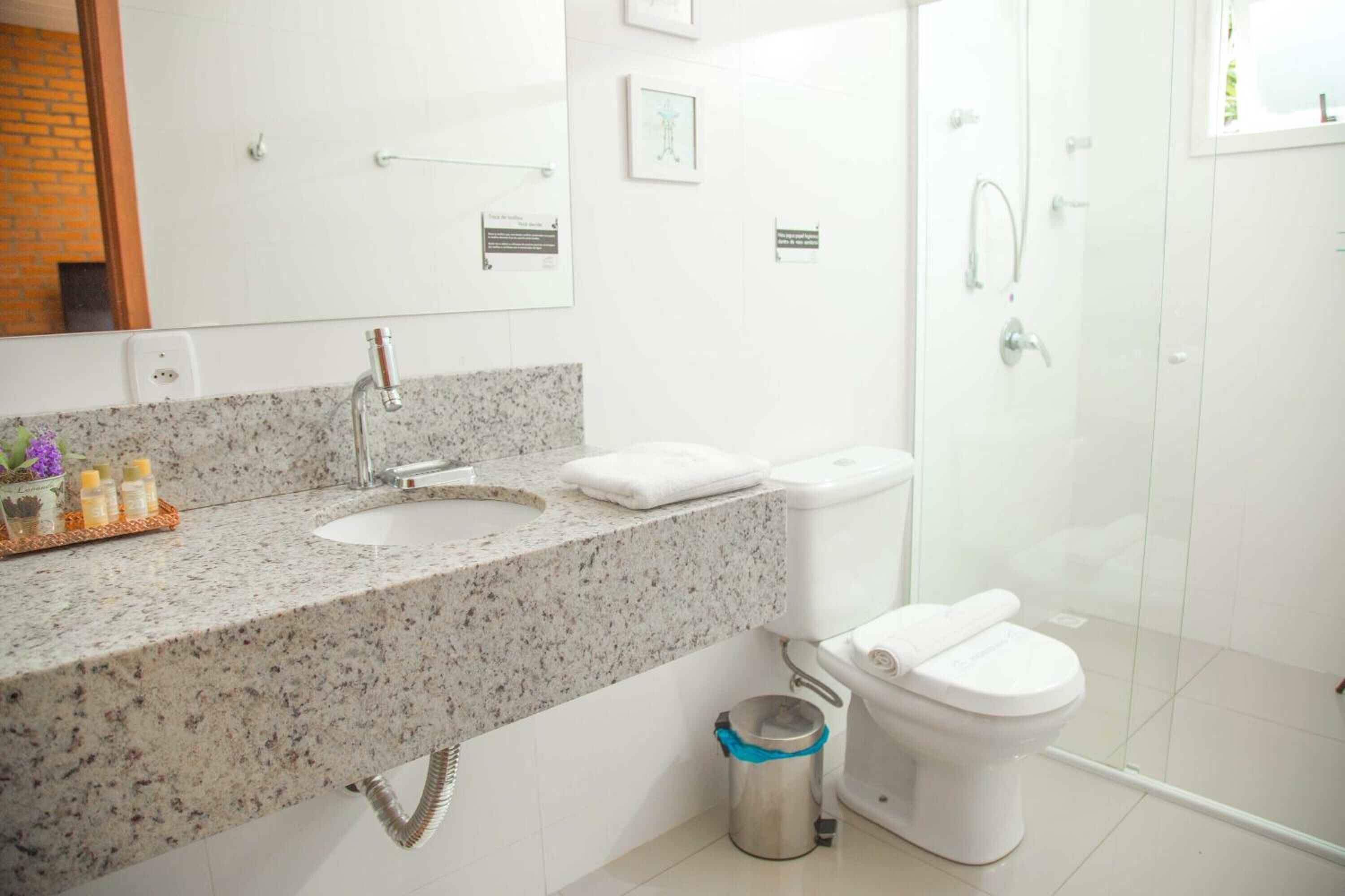 Ein modernes Badezimmer mit einer Granit-Arbeitsplatte, weißen Sanitärobjekten und einer Duschkabine aus Glas.