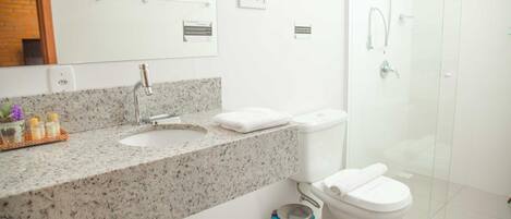 Ein modernes Badezimmer mit einer Granit-Arbeitsplatte, weißen Sanitärobjekten und einer Duschkabine aus Glas.