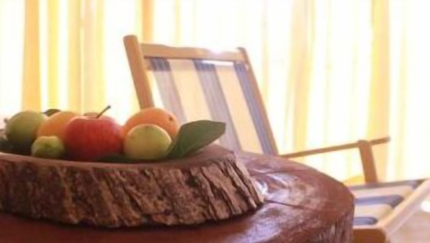 A wooden table with a carved edge and a fruit arrangement on top.