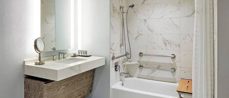 A modern bathroom with a marble shower, a wooden vanity, and a bathtub.