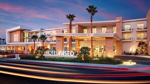 A modern hotel with a prominent entrance, multiple balconies, and palm trees. - Hotel Paseo, Autograph Collection by Marriott (Palm Desert)