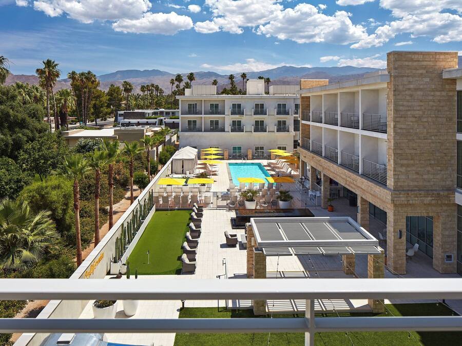 A hotel with a rooftop pool, outdoor seating, and a view of mountains.