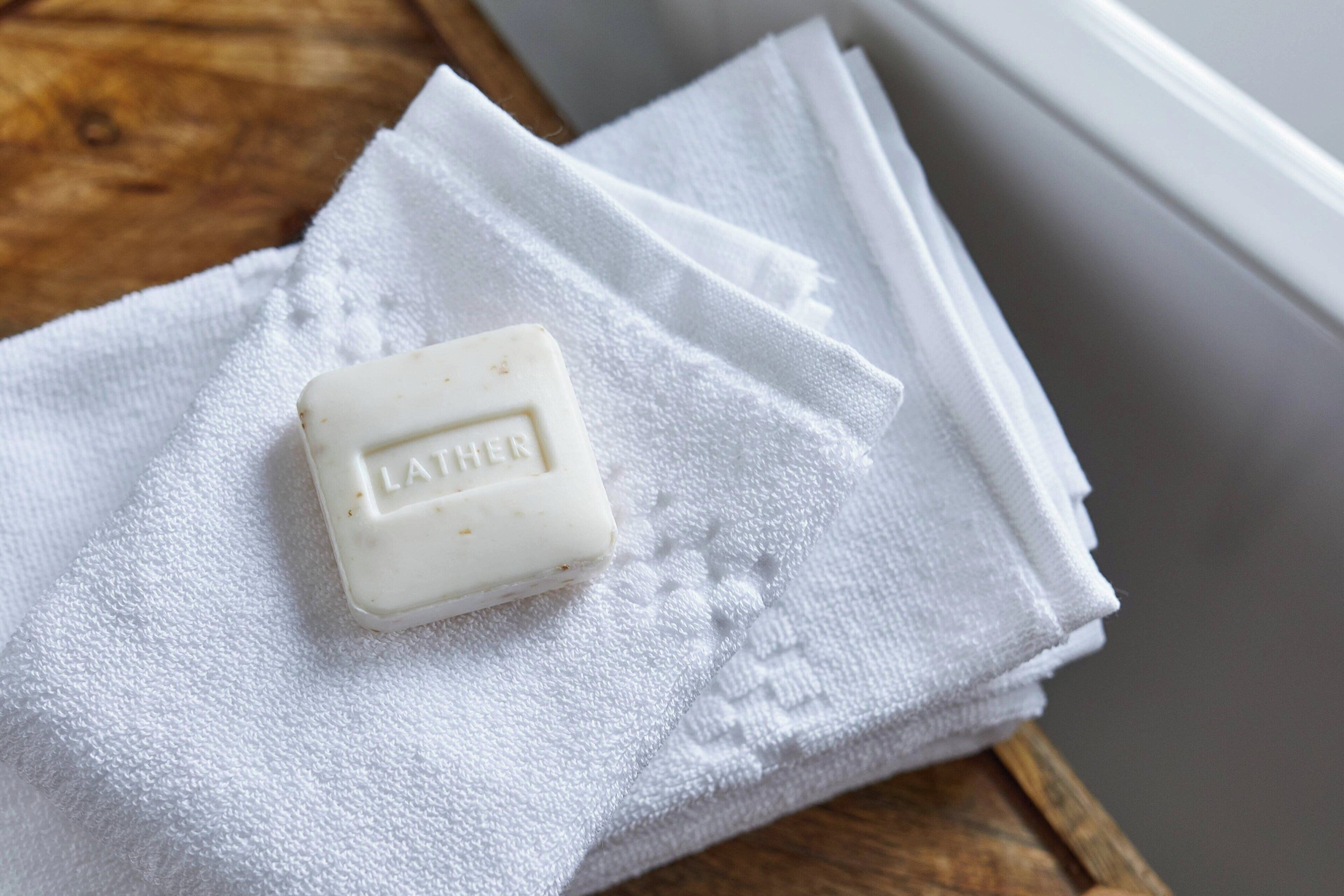 Un pain de savon portant l’inscription « LATHER » sur une serviette blanche.