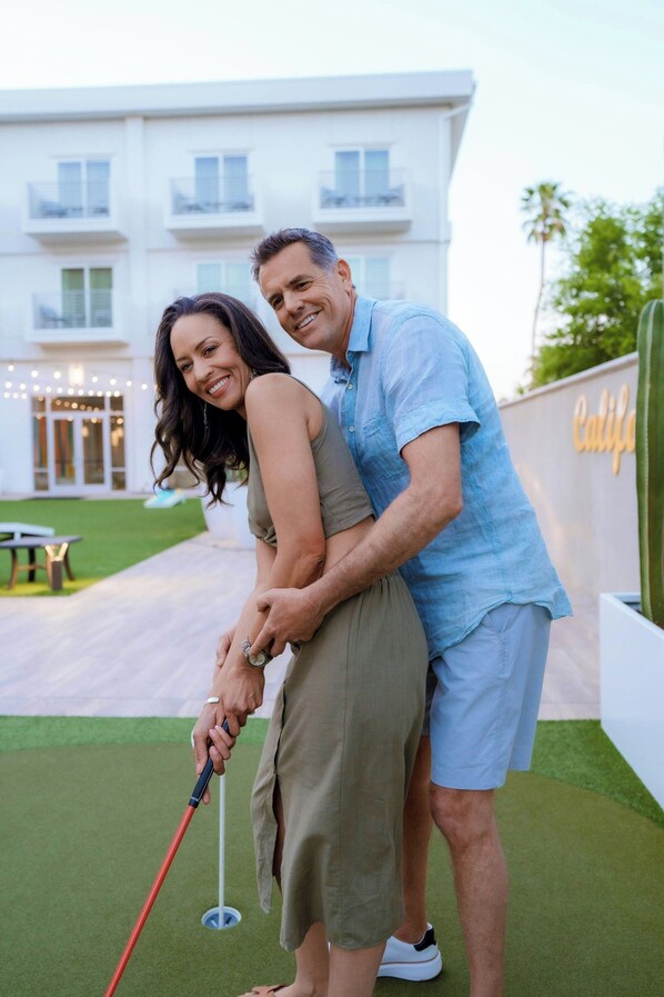 A couple on a golf course with a building in the background.