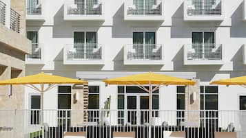 Un hotel con area piscina, posti a sedere all'aperto e facciata bianca.