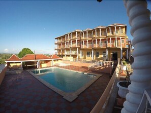 A hotel with a swimming pool, multiple balconies, and a view of the landscape. - Paradise Reggae Resort (Spanish Town)