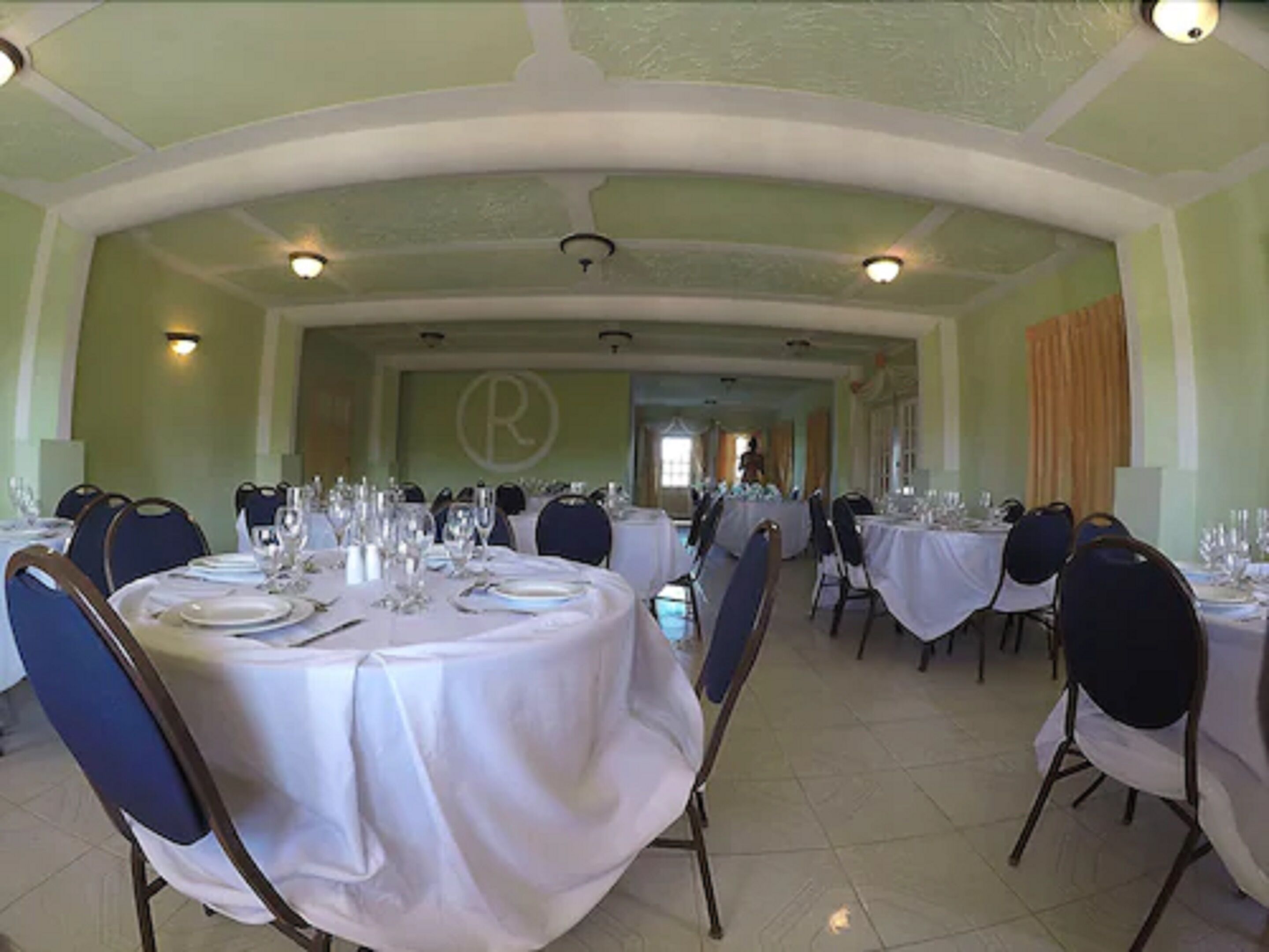 A formal dining room with round tables, chairs, and white tablecloths.