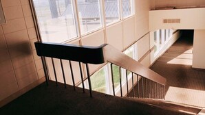 A staircase with a black handrail and a view of the outside through large windows. - Hi Valley Motor Inn (Valleyview)
