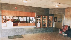A reception area with a counter, wooden cabinets, and a stone wall. - Hi Valley Motor Inn (Valleyview)