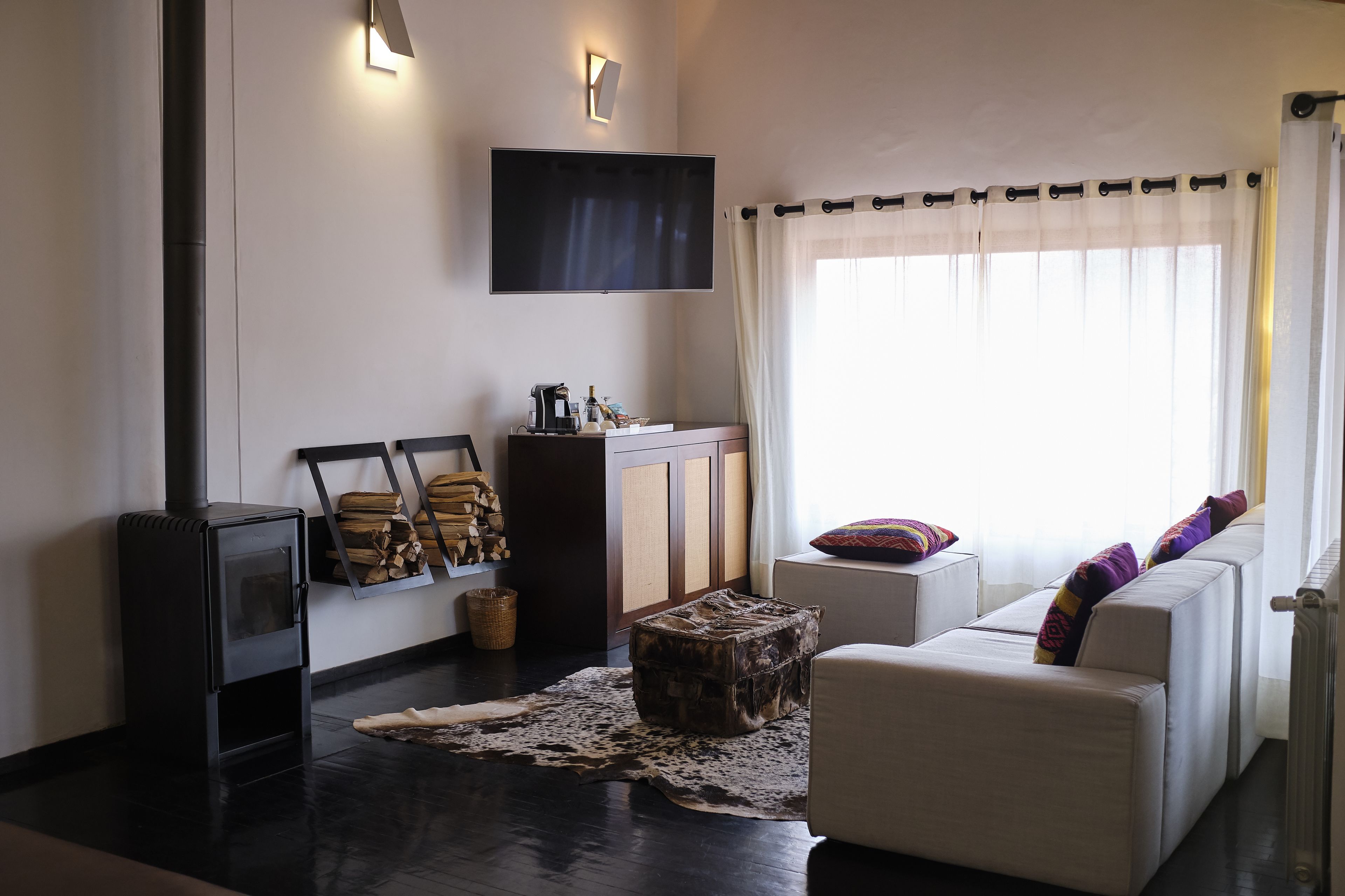 Una sala de estar con sofá, televisión, chimenea y un ventanal con cortinas.