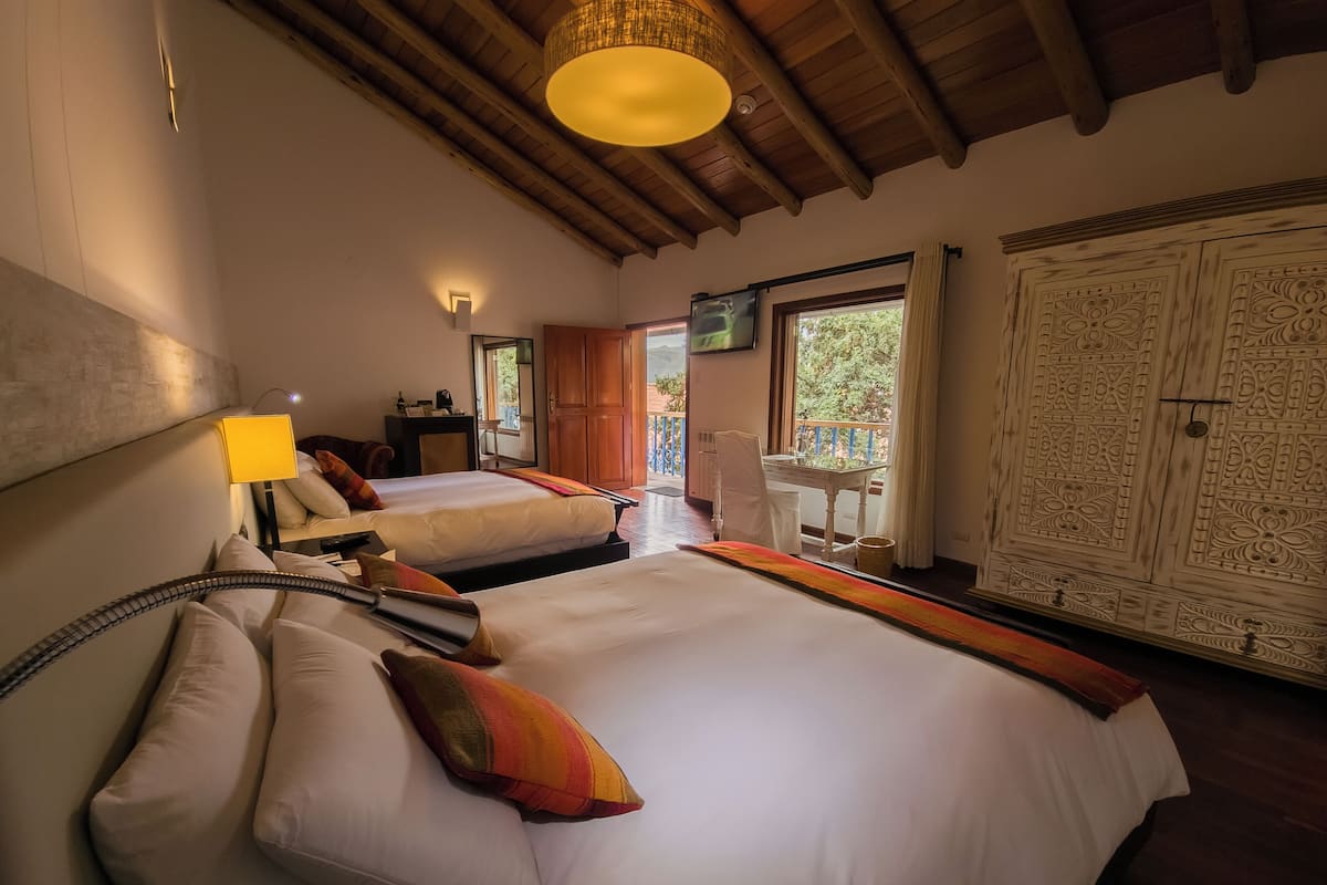 Une chambre d’hôtel avec deux lits, un balcon, une télévision et un plafond en bois.