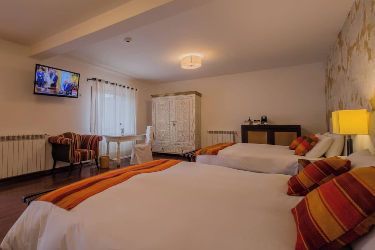 Une chambre d’hôtel avec deux lits, un bureau, une télévision et une armoire.