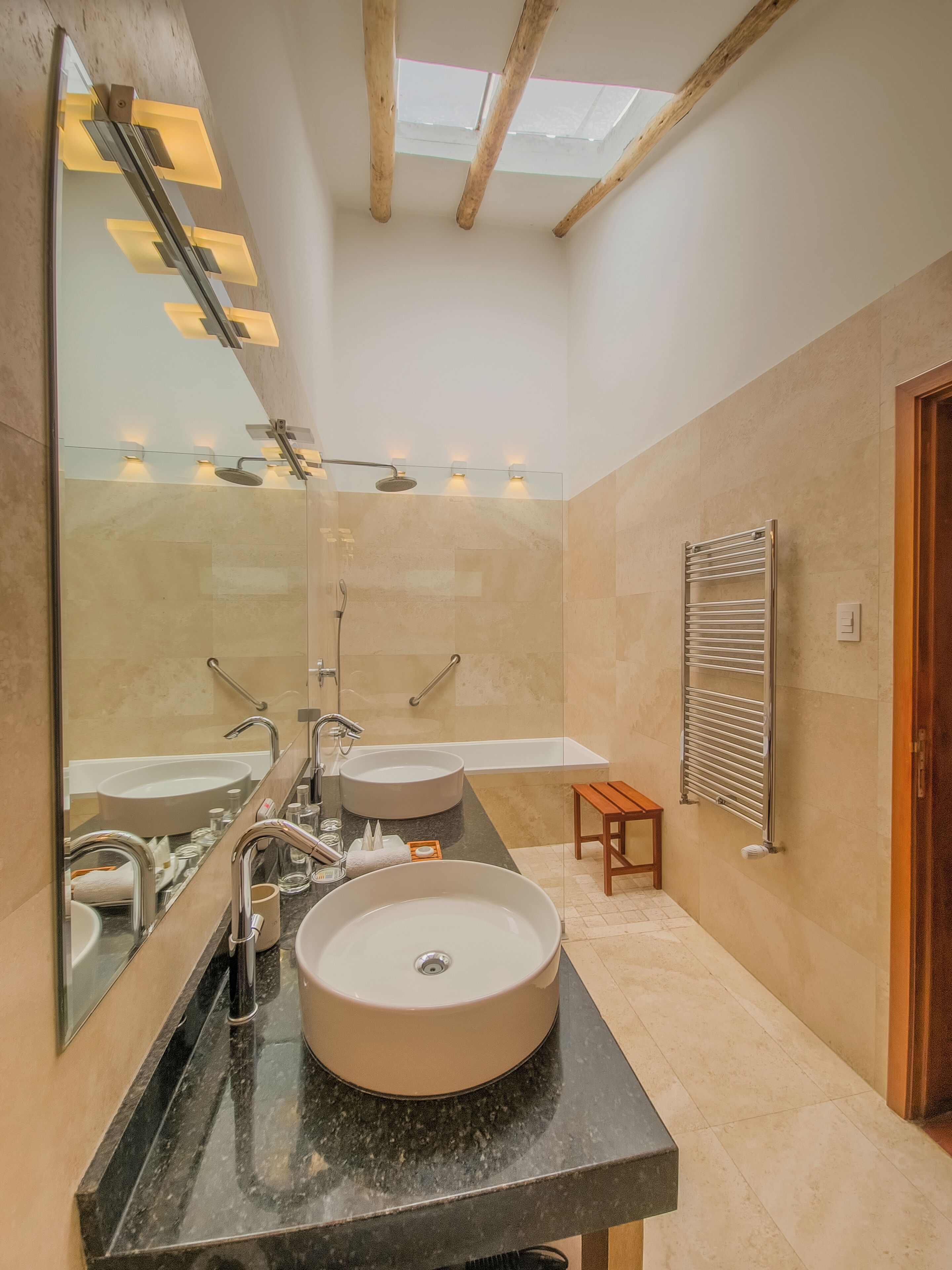 A modern bathroom with a large mirror, two sinks, a shower, and a towel rack.