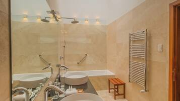 A modern bathroom with a large mirror, two sinks, a shower, and a towel rack.