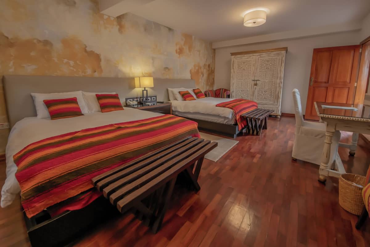 Une chambre d’hôtel avec deux lits, un bureau, une chaise, une lampe et une armoire.