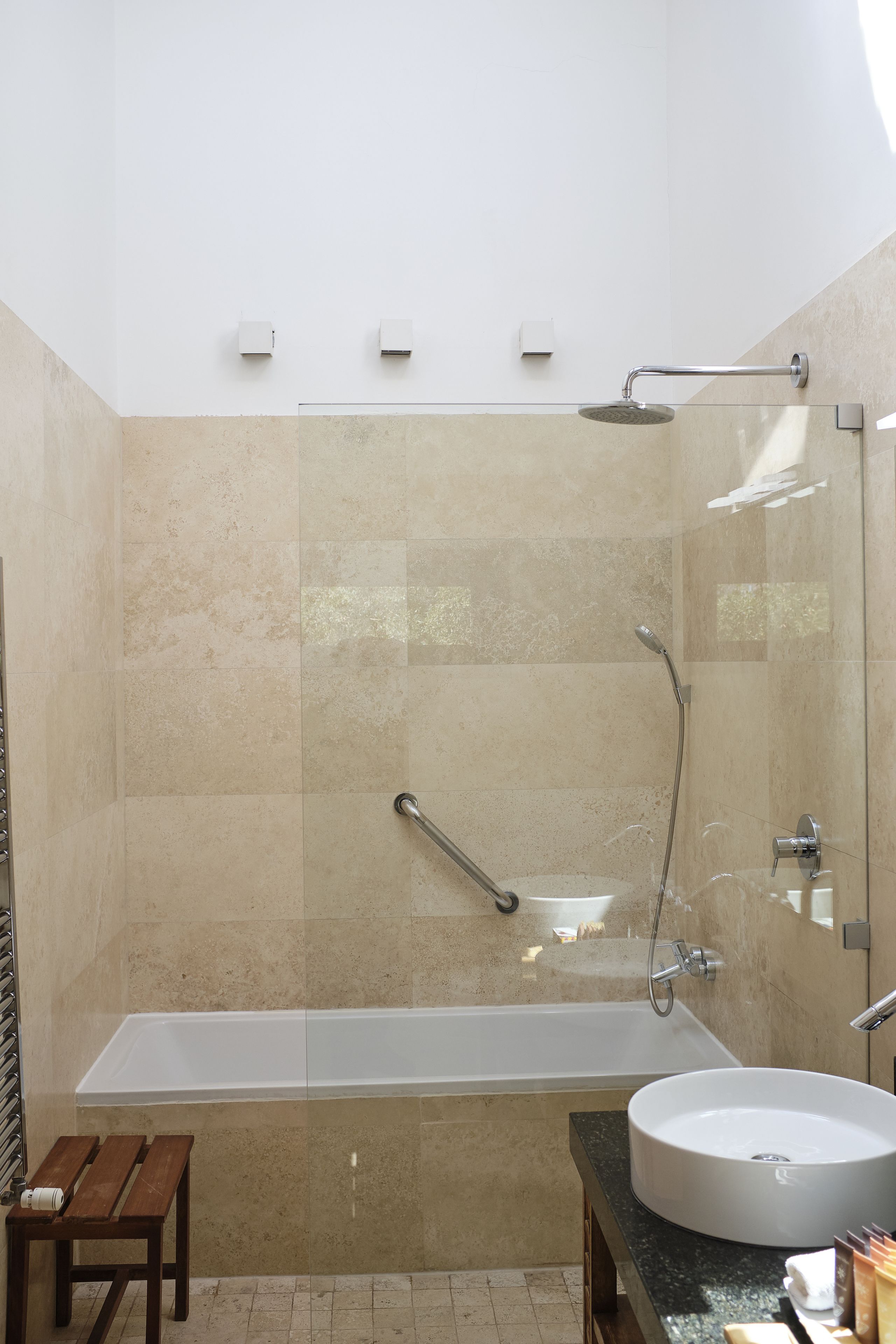 Un baño moderno con una bañera, un lavabo redondo y un banco de madera.
