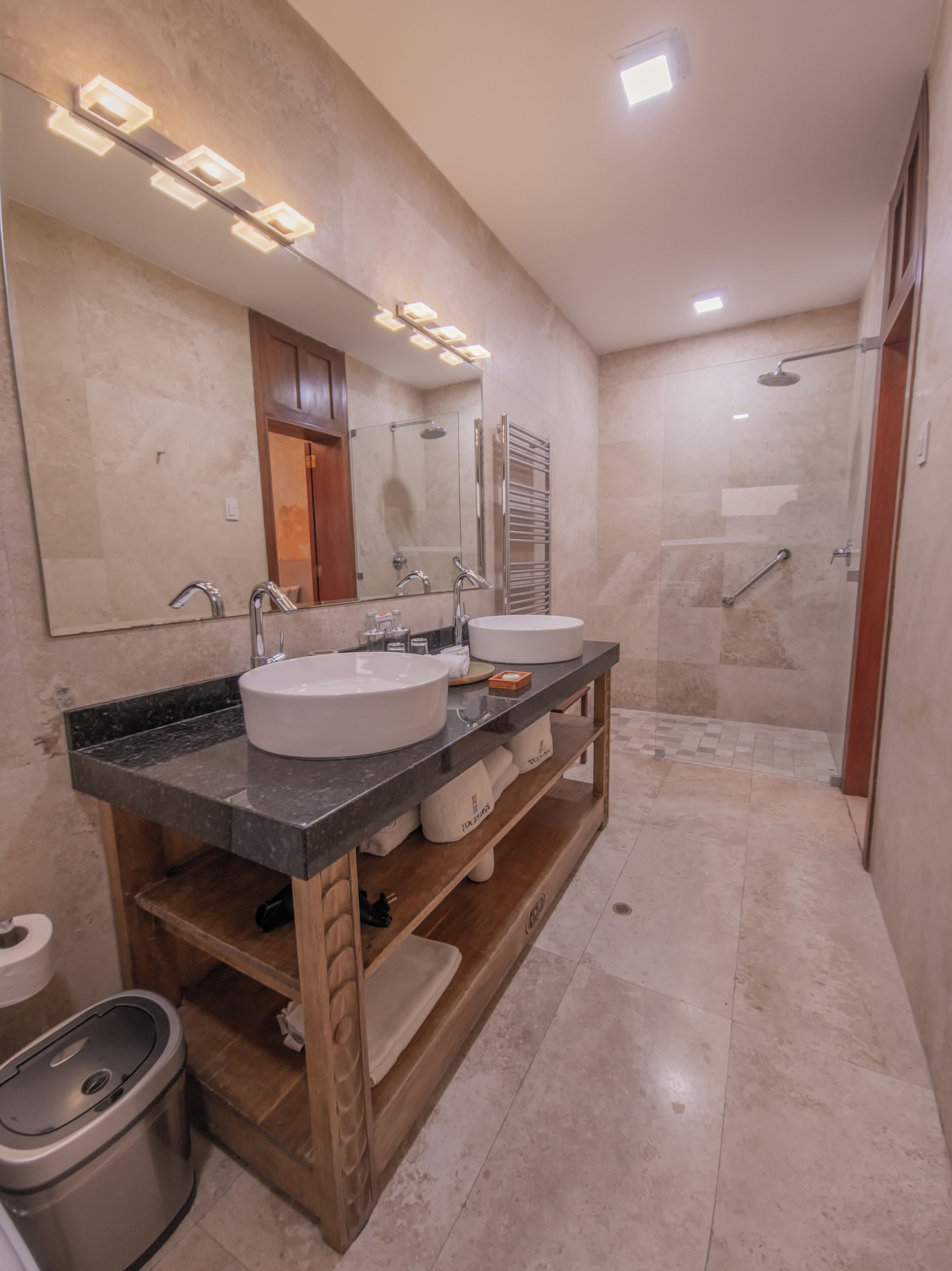 A modern bathroom with two sinks, a mirror, and a shower.