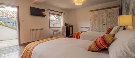 A bedroom with two beds, a TV, a desk, and a door with intricate patterns.