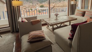 Una habitación con un ventanal grande, una mesa de madera y dos sofás con cojines.