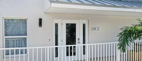 A white building with a balcony, a door, and a window.