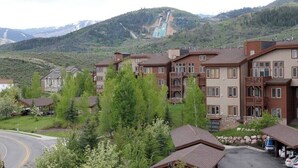 A residential area with multi-story buildings, a parking area, and a mountainous backdrop with a waterfall.