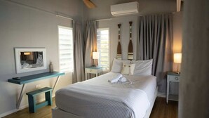 Et soveværelse med seng, skrivebord, stol, ventilator og et vindue.