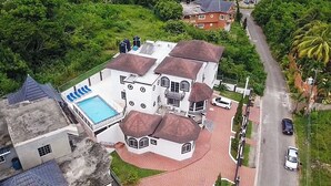 Un bâtiment blanc doté d’une piscine, de plusieurs toits et d’une allée pavée.