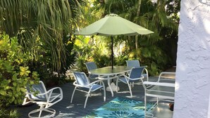 Eine Terrassenanlage im Freien mit Tisch und Stühlen, umgeben von üppigem Grün.