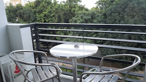 A balcony with a round table and two metal chairs, a radiator, and a view of trees and buildings. - First Class Apartment, Best kept Secret in Angeles City ! 
Perfect location! (Angeles City)