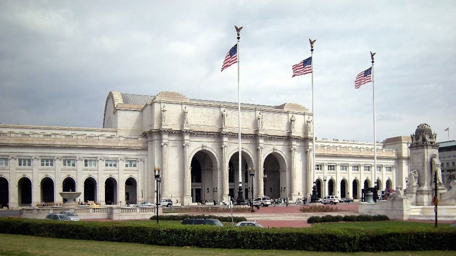 A large, classical building with multiple arches and American flags.