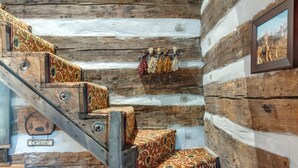 Una escalera de madera con peldaños cubiertos de un estampado de alfombra, un cartel de 'Welcome' y un cuadro en la pared.