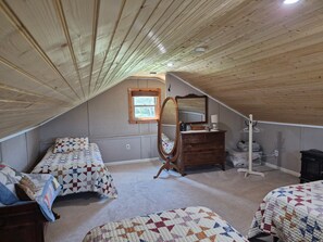 A bedroom with two beds, a dresser, a mirror, and a window.