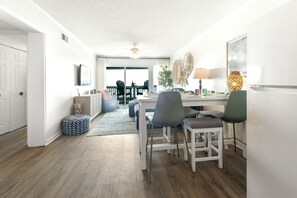 Een moderne keuken met witte kasten, een eethoek met een tafel en stoelen, en uitzicht op de eetkamer.