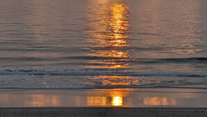 A sunset over a calm sea with clouds reflecting the sunlight. - Beautiful Top Floor Oceanfront Condo, Breathtaking Views from
Oceanfront Balcony (Carolina Beach)