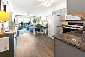Een moderne keuken met granieten aanrecht, een witte koelkast en een eethoek met een tafel en stoelen.