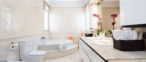 Un baño moderno con inodoro, bidé, bañera y un espejo grande.