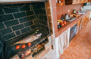 A kitchen with a brick oven, a sink, and various cooking utensils.