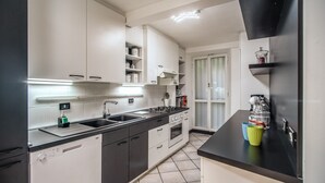 Una cocina moderna con armarios blancos, encimera negra y lavavajillas.